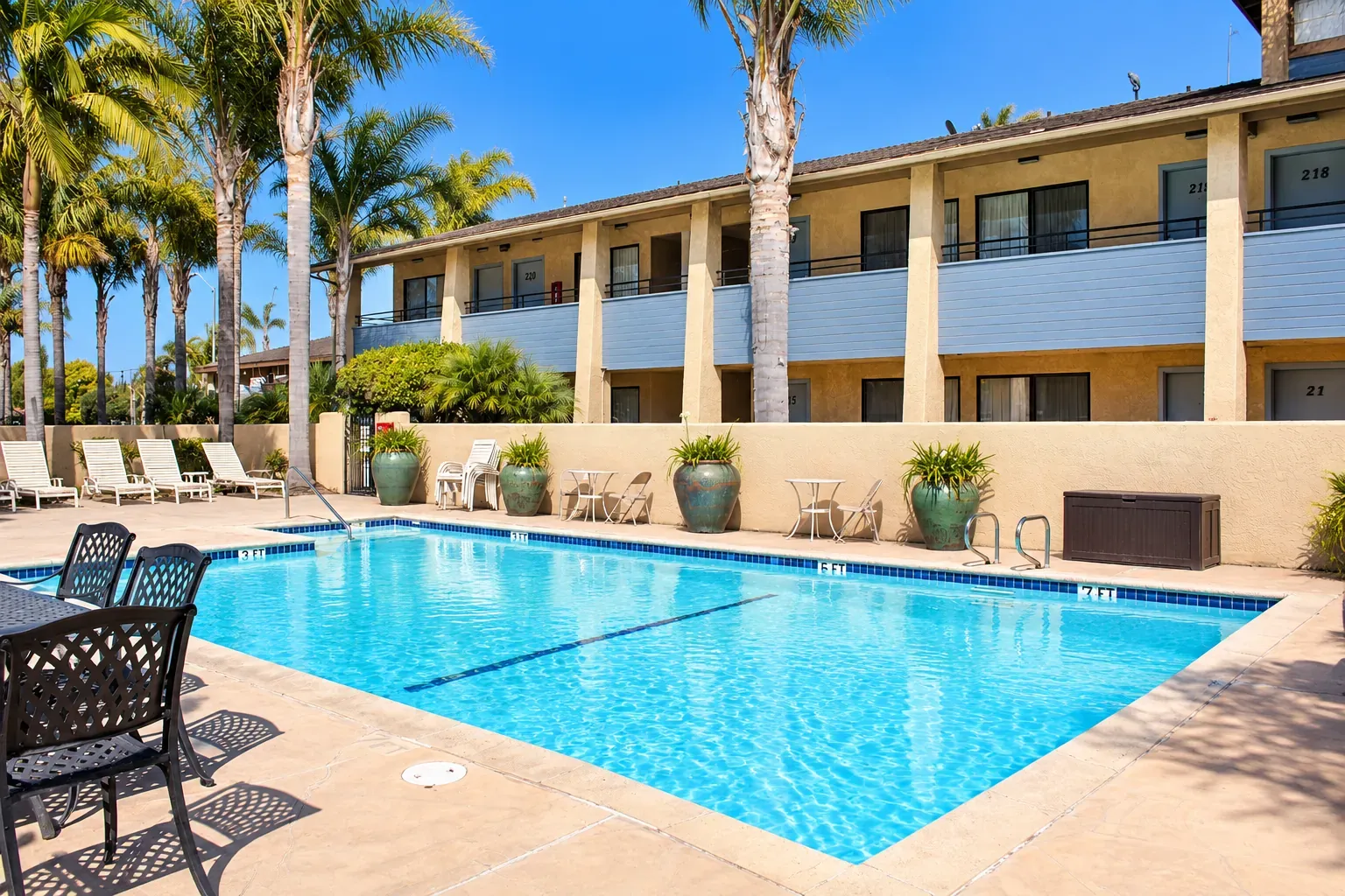 The outdoor pool beside the two-story guest wing, with patio chairs and potted plants