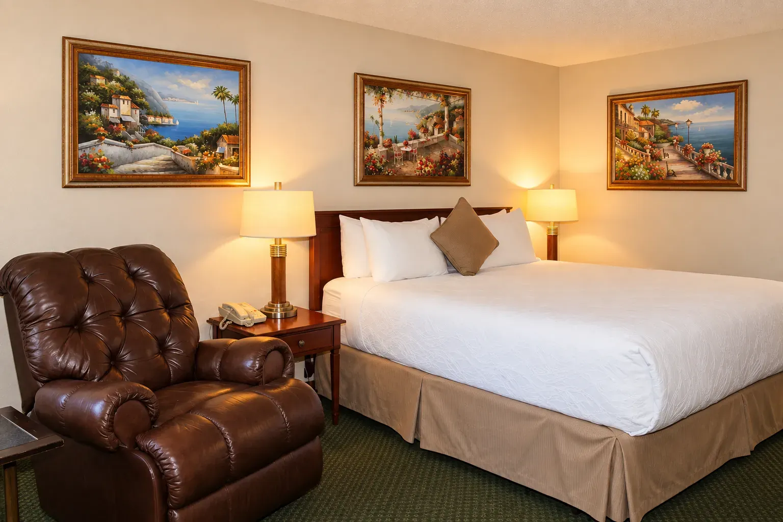 A guest room with one bed, a leather recliner and framed coastal paintings